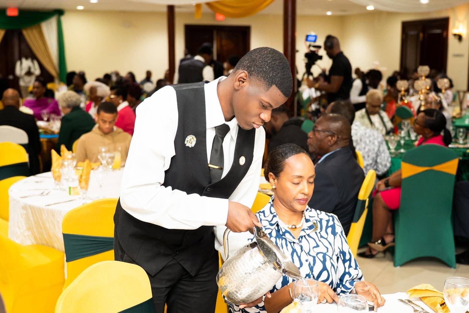 Top Tier Butlers server pouring water for a guest at a banquet