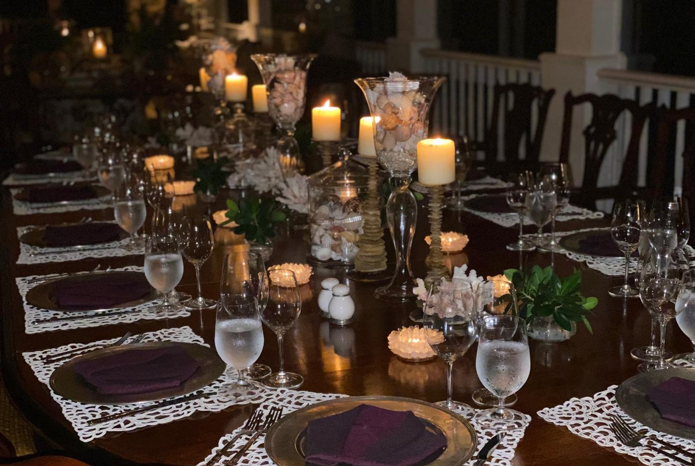 Candlelit dinner table with silver chargers, crystal glassware and shell centrepieces