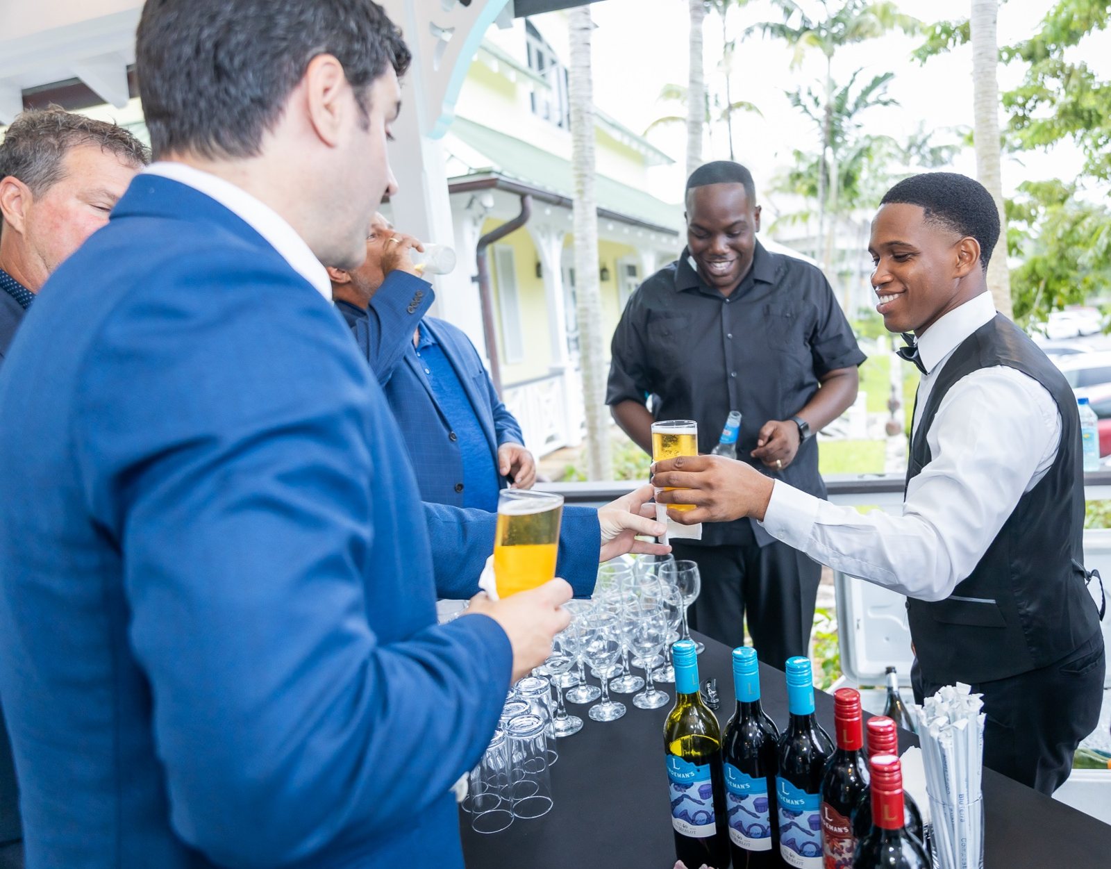 Top Tier Butlers bartender handing a drink to guests at an outdoor reception